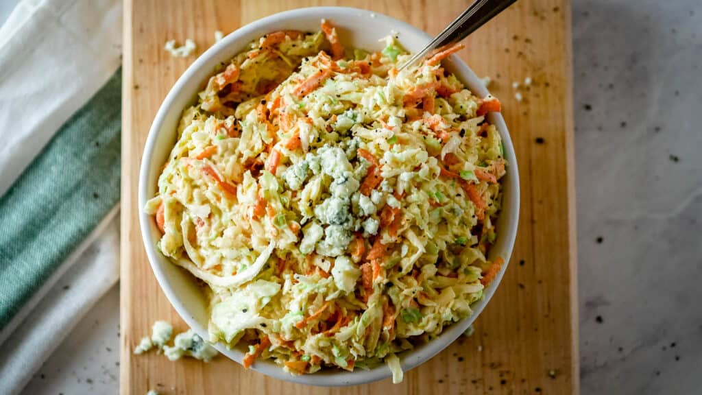 Top view of a bowl of coleslaw with blue cheese on top.