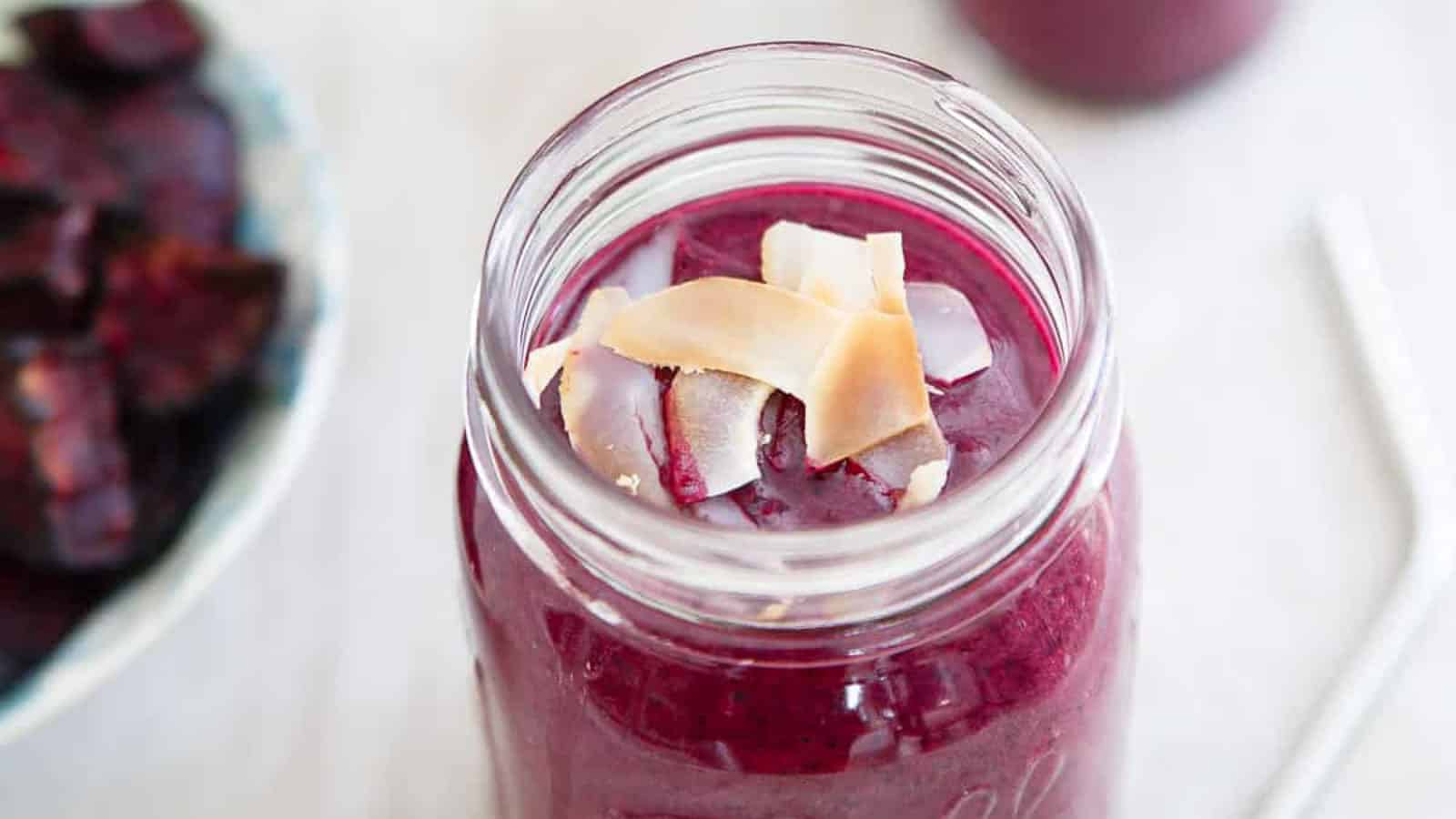 Wild blueberry beet smoothie in a mason jar topped with toasted coconut.