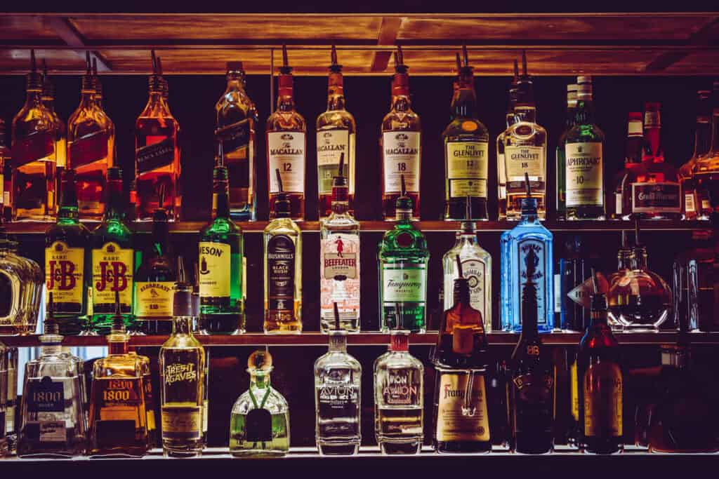 bottles of alcohol line the shelves of a bar. 