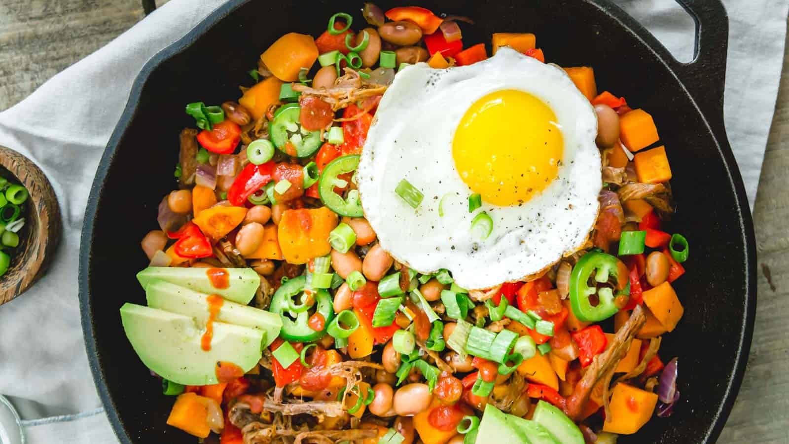 Brisket hash with a fried egg in a cast iron skillet.