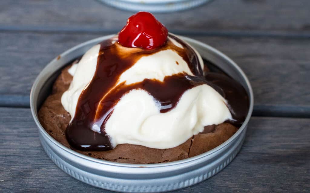 Brownie sundae cookie topped with vanilla ice cream and a cherry.