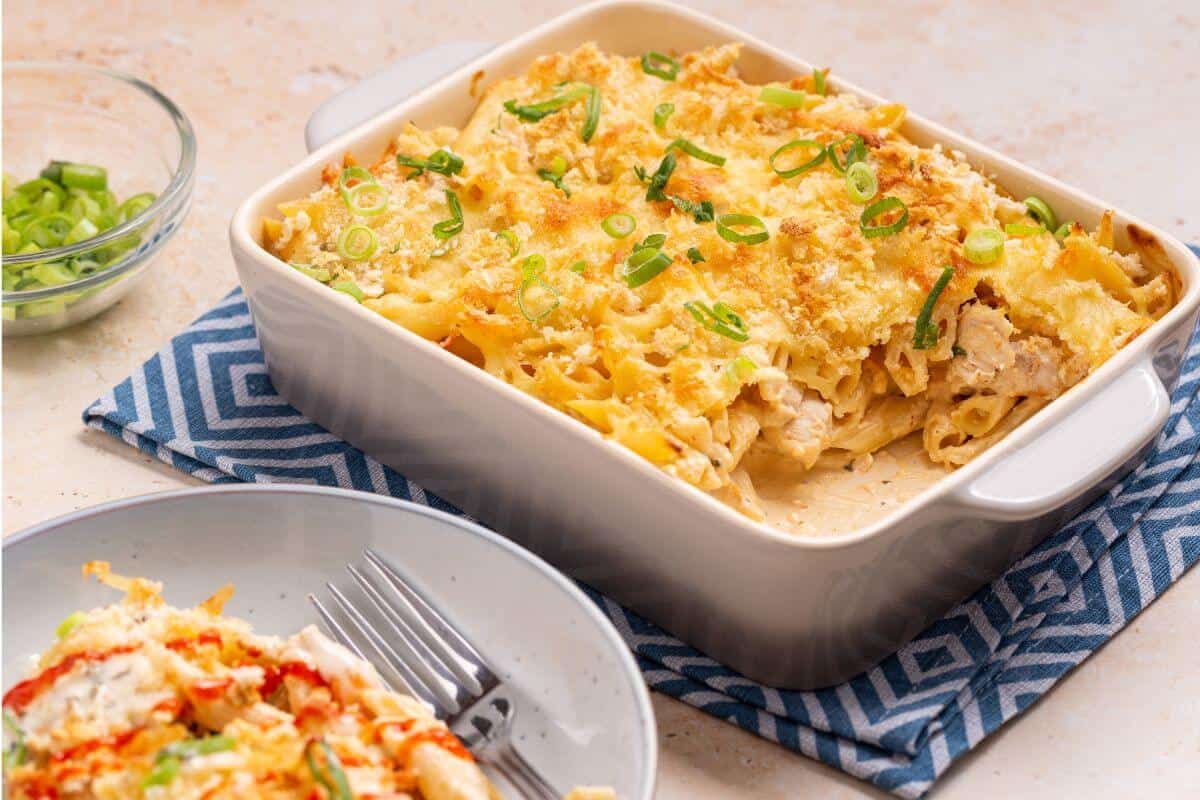 Serving of buffalo chicken pasta bake with casserole dish.