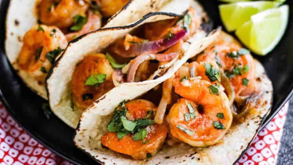 Shrimp tacos with lime wedges.