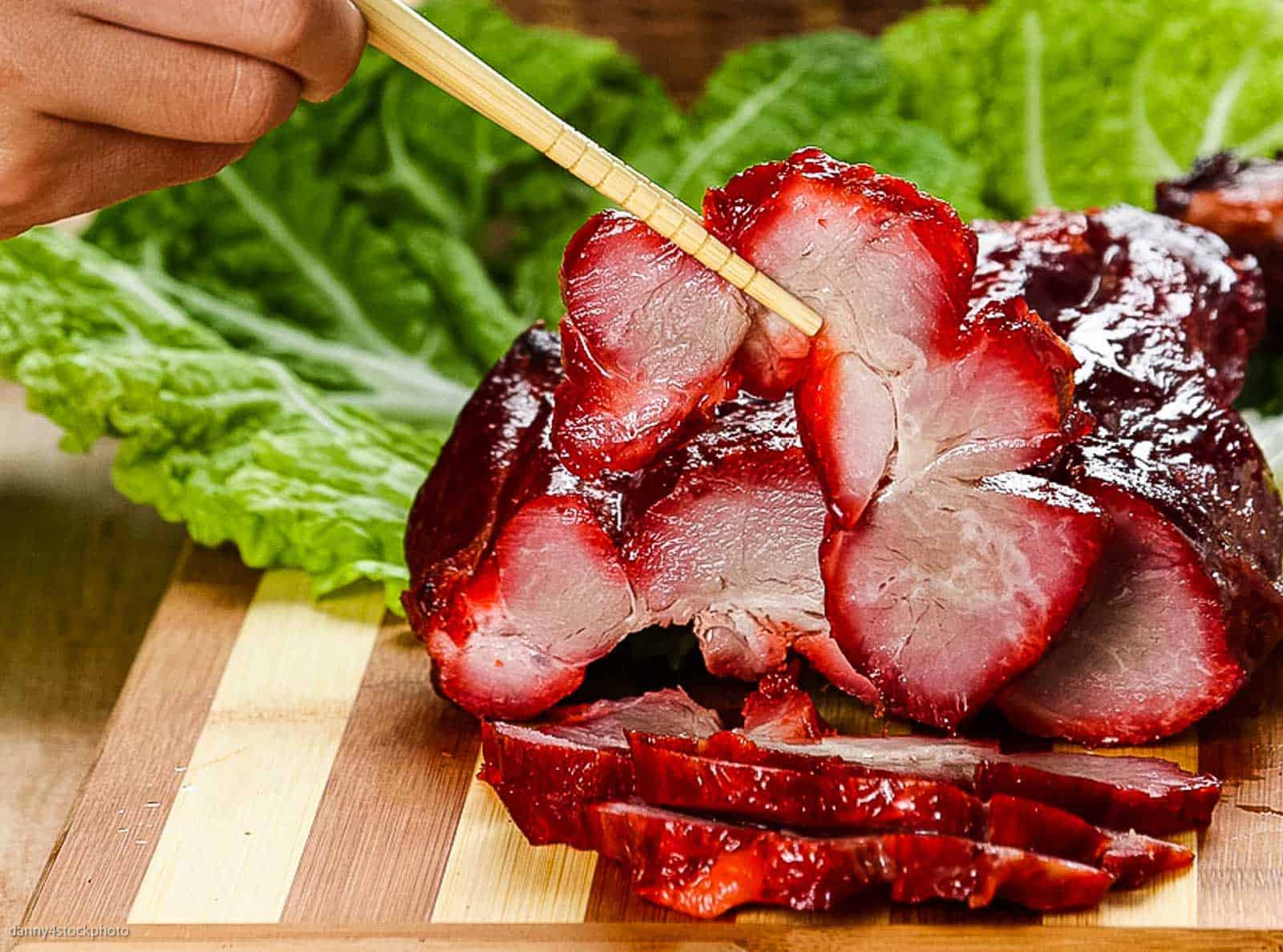 Sliced char siu with chopsticks.