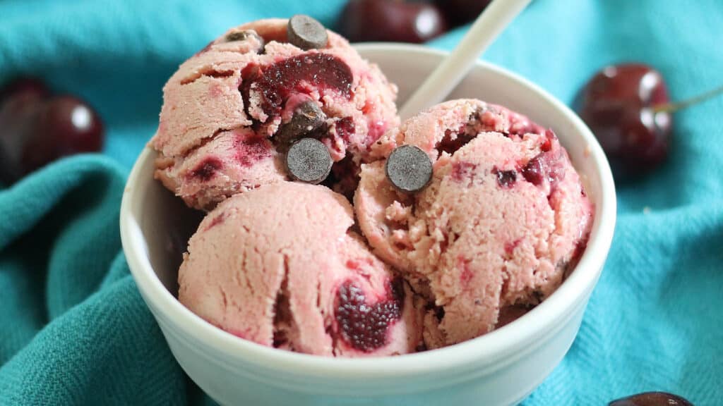 Cherry chocolate chip frozen yogurt in a white bowl on a turquoise kitchen towel. 