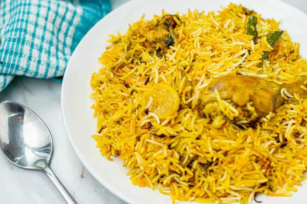 Chicken biryani on a plate with raita.