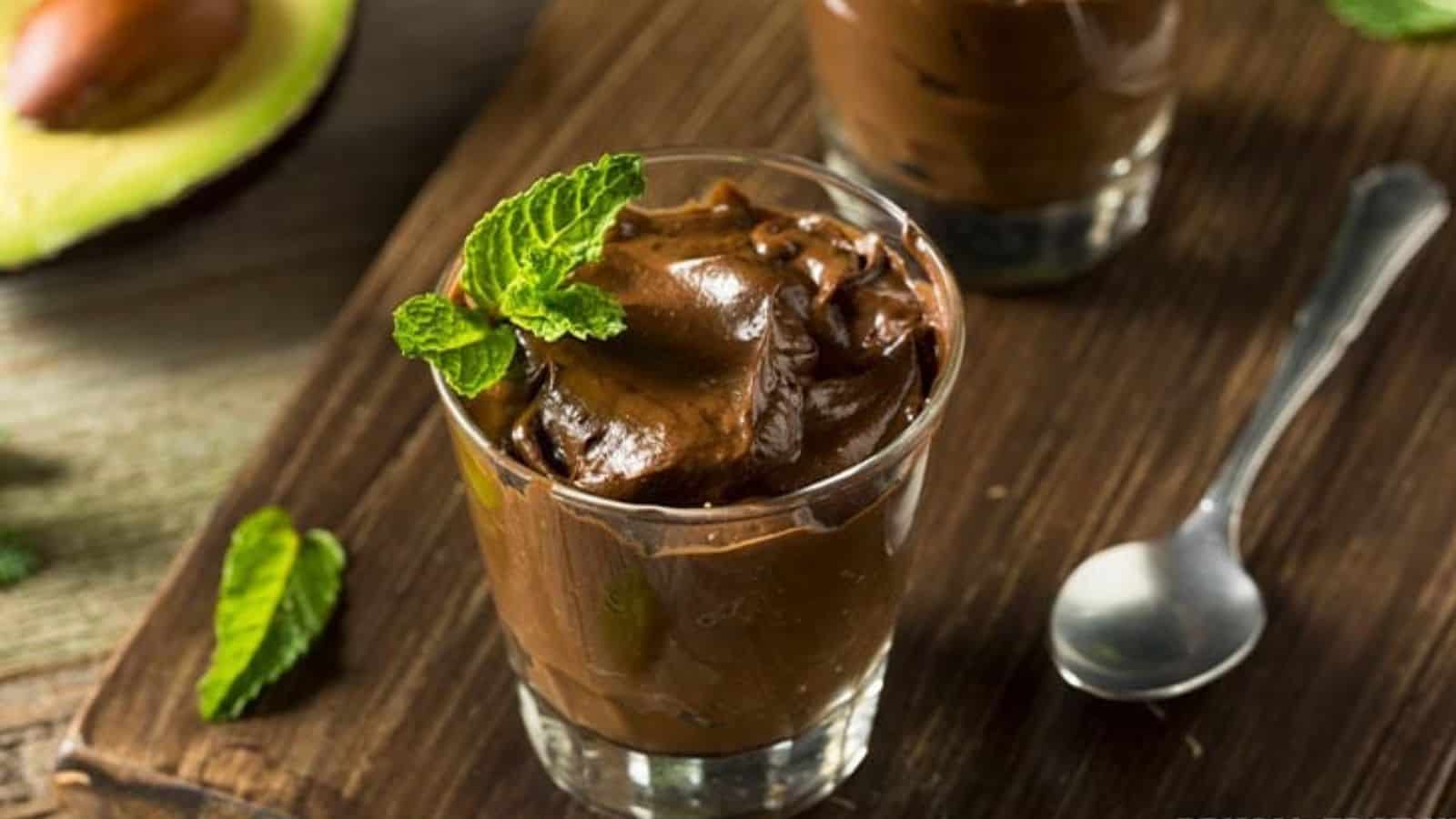 Chocolate avocado pudding in glass with spoon.