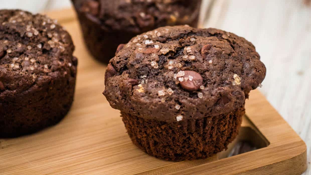 Double chocolate muffins on a wooden cutting board.