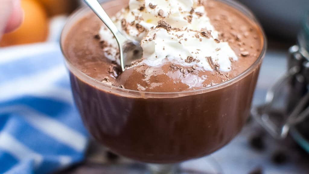 Homemade chocolate pudding in a bowl with whipped cream.
