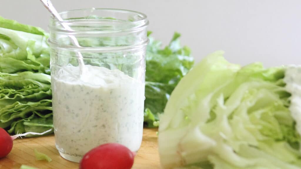 Creamy 3-herb dressing in a glass jar with a spoon.