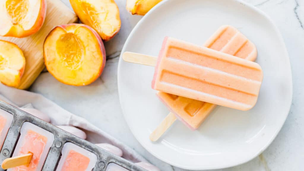 Creamy peach popsicles on a plate.