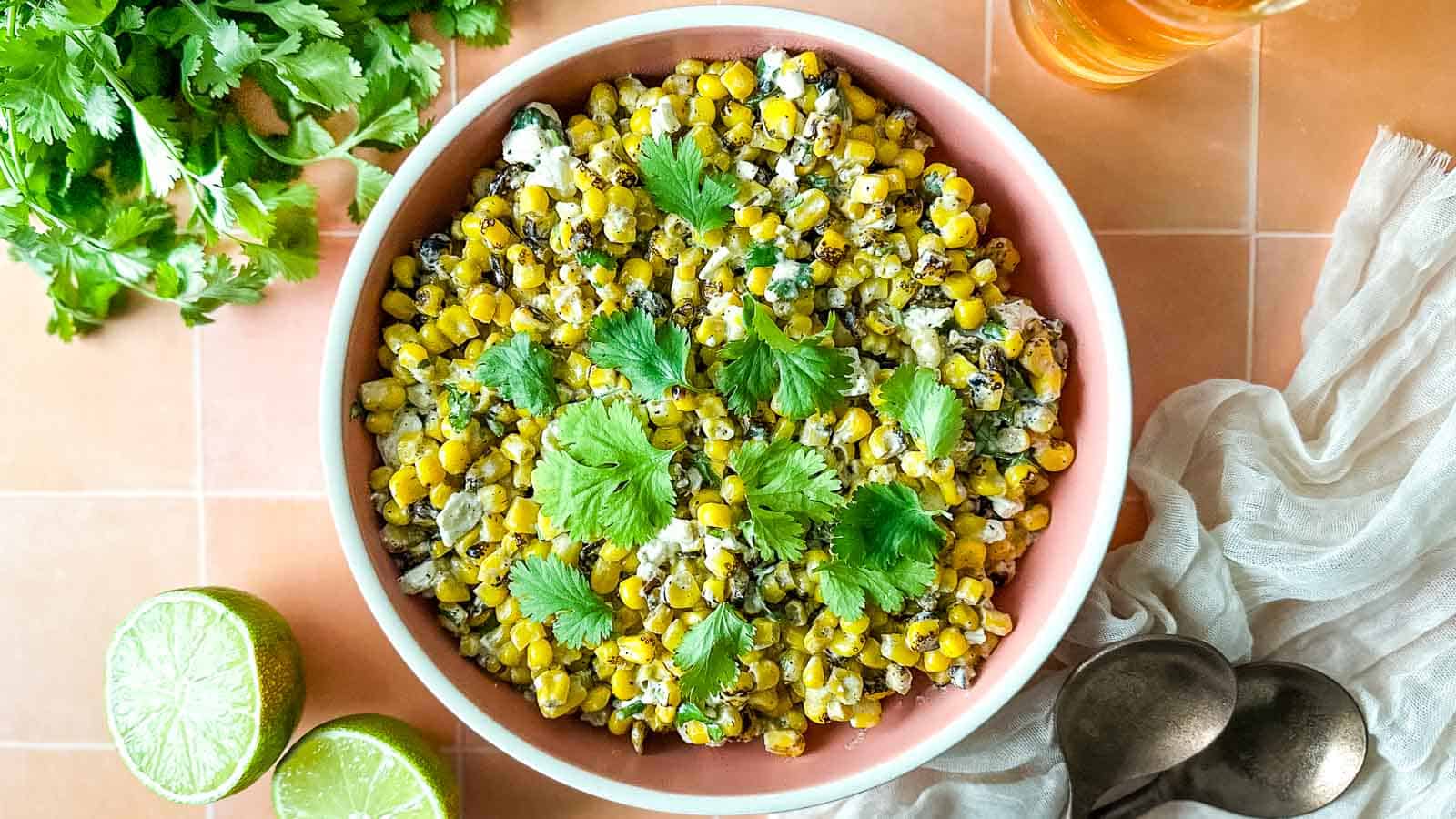 esquites in a black bowl with a lime wedge.