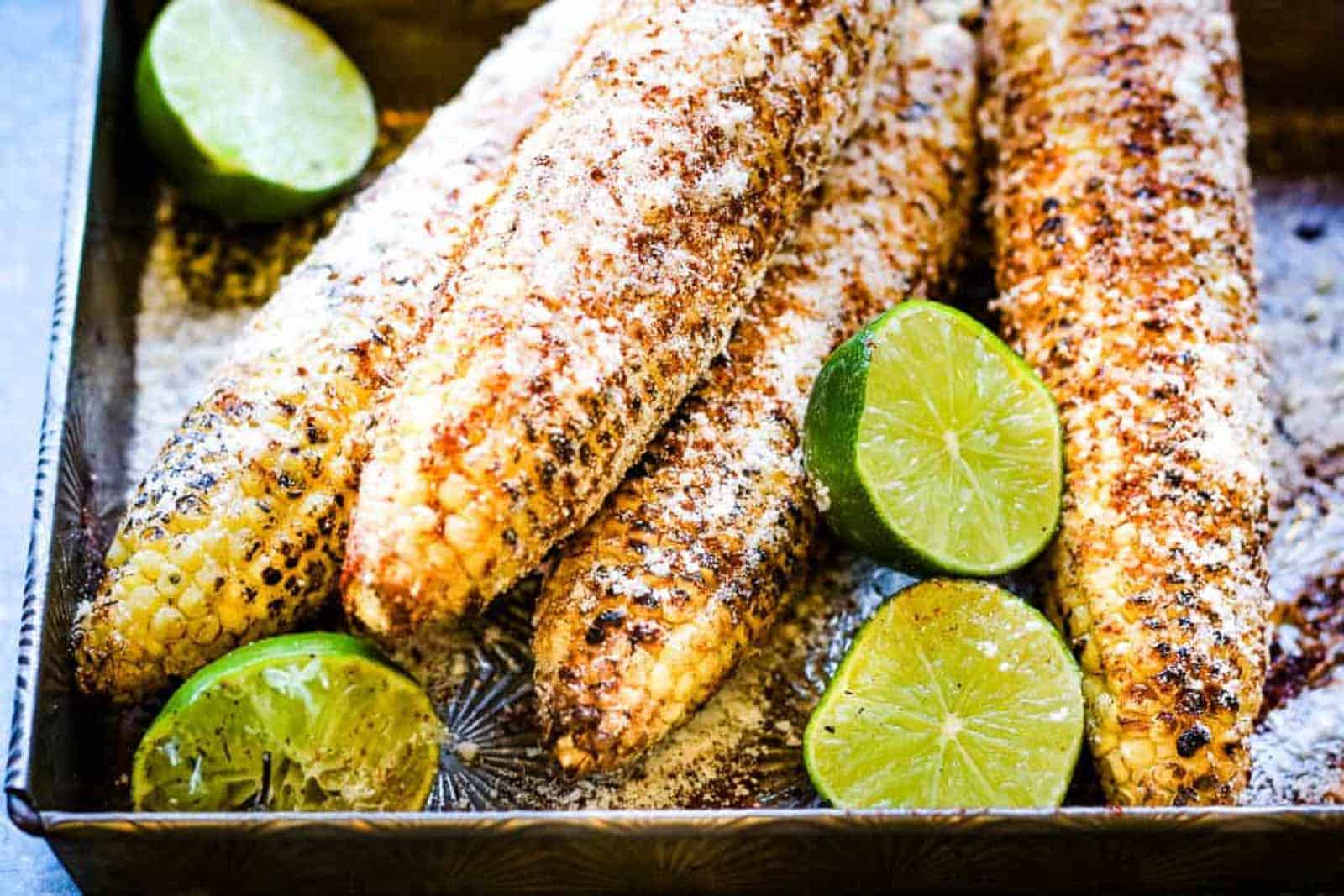 metal baking pan with elote, Mexican grilled corn cobs with mayonn