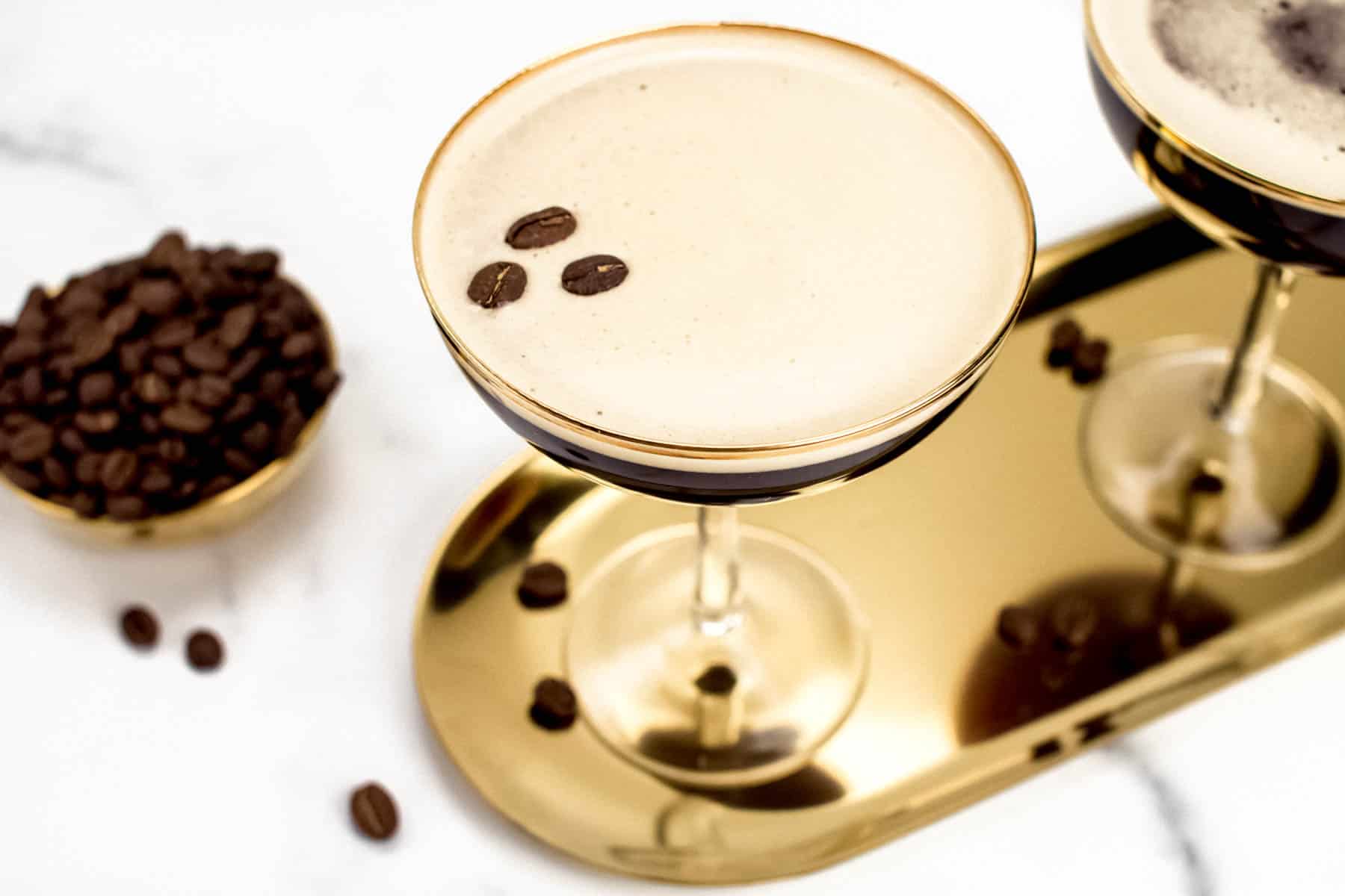 espresso martinis in coupe glasses on a gold tray.