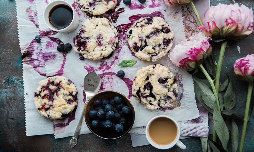 A picture of low-carb blueberry scones recipe on table with flowers.