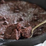 Skillet brownie in a cast iron pan with a spoonful showing.