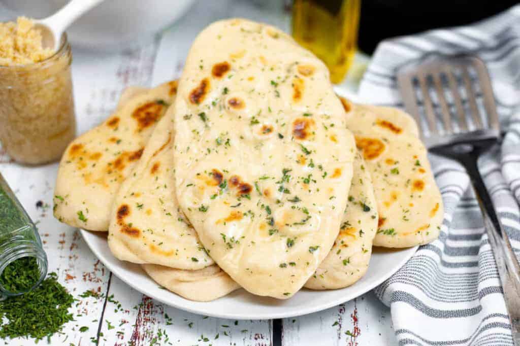 Low angle shot of a pile of garlic butter naan on a plate.