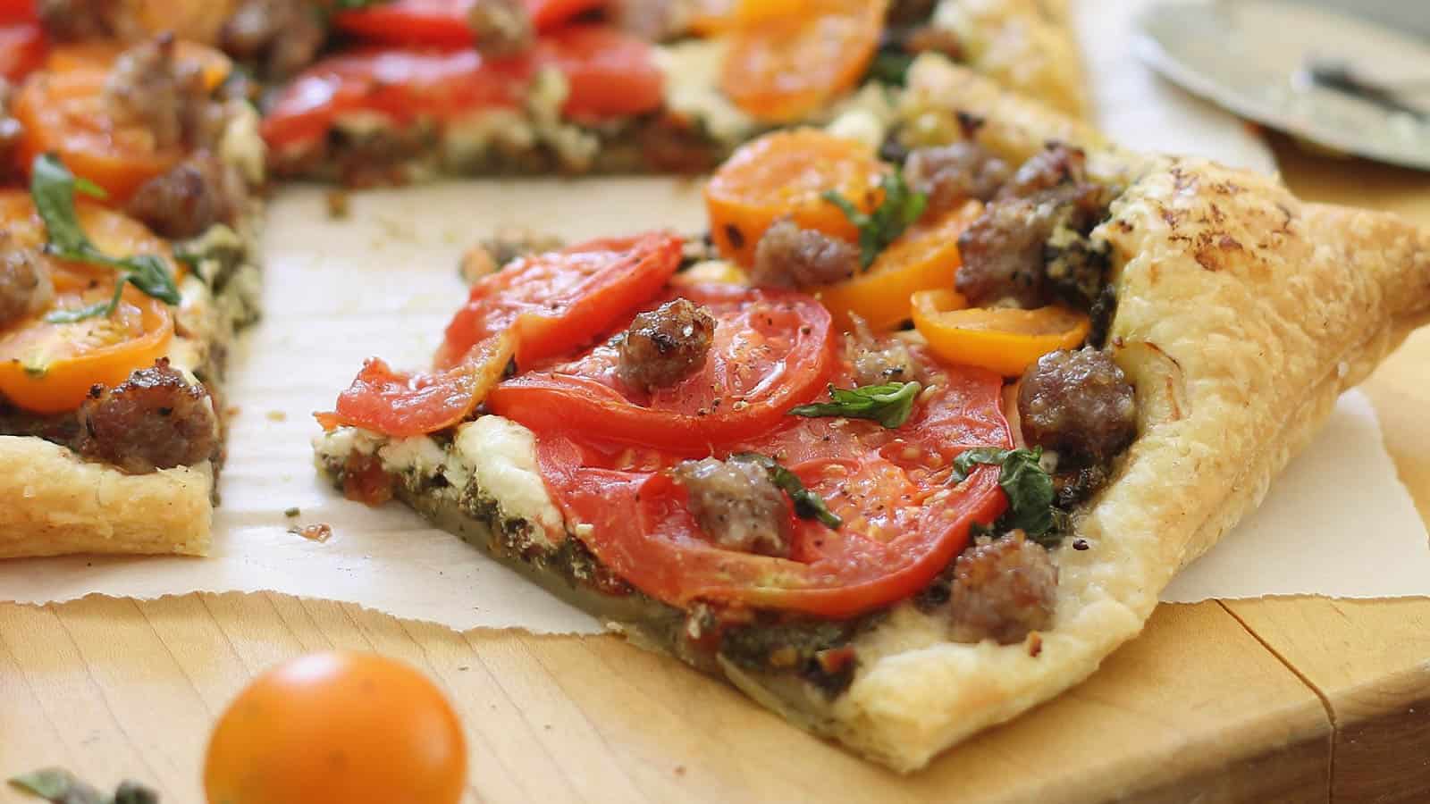 Goat cheese tomato sausage tart on a cutting board.