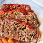two slices of meatloaf on a plate with mashed potatoes and carrots.