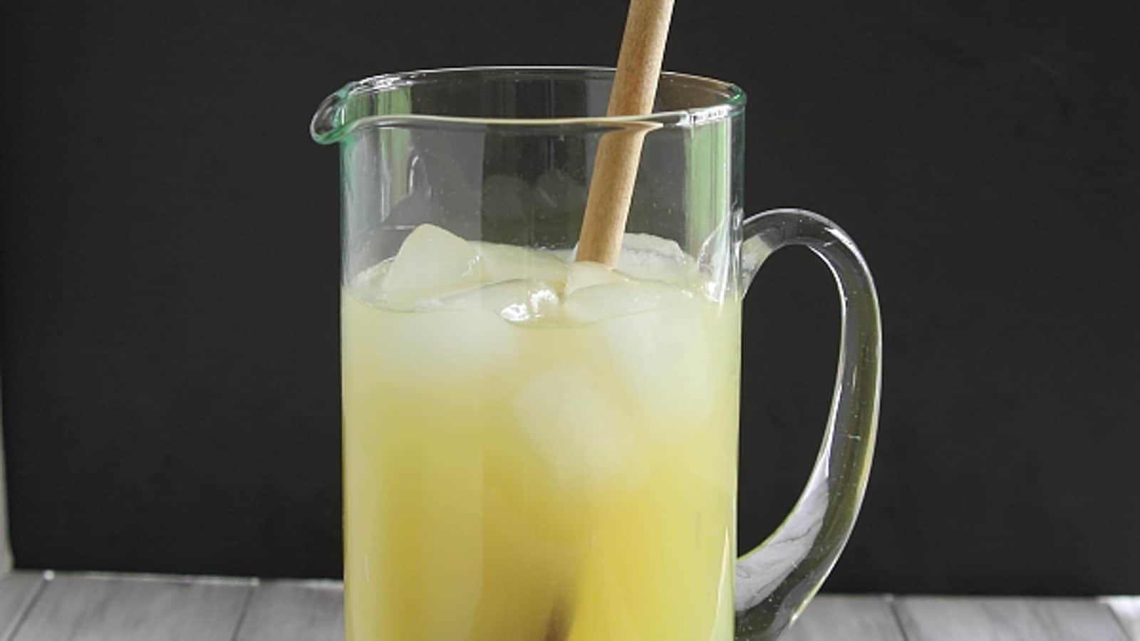 Sports drink in a large glass pitcher with wooden mixing spoon.