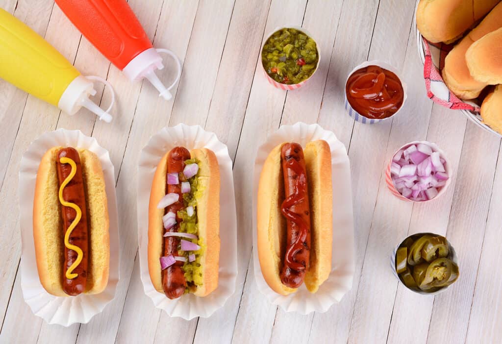 three hot dogs with condiments.