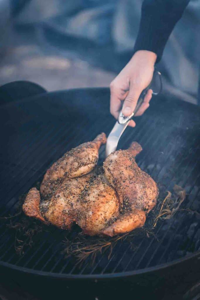 spatchcock chicken being removed from the grill. 