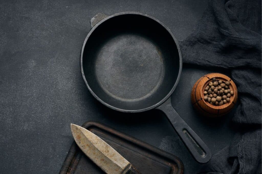 Cast iron skillet with knife and bowl of peppercorn