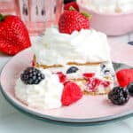 Icebox cake with raspberries, blueberries and strawberries on a pink plate.