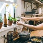 Young woman cutting fresh herbs in kitchen.