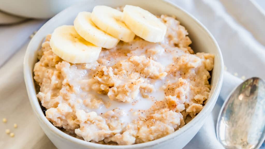 Creamy millet porridge in a small bowl with banana slices.