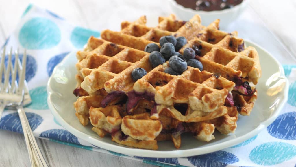 Blueberry oatmeal pancakes on a plate topped with blueberries.