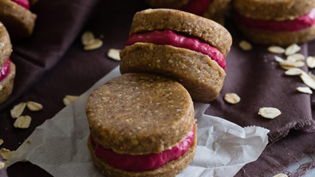 Oatmeal raspberry sandwich cookies on parchment paper.