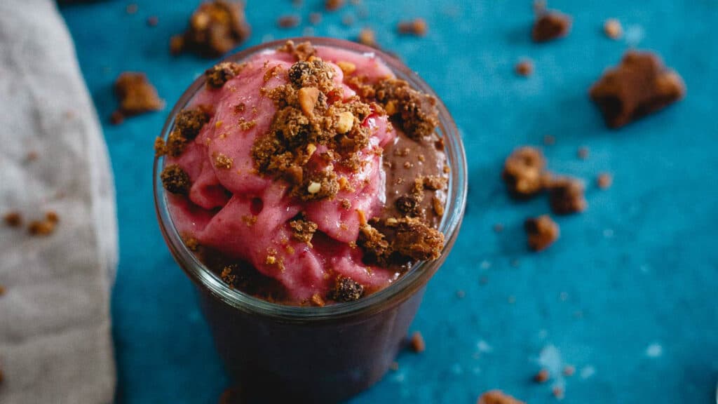 Peanut butter chocolate chia pudding in a glass jar with frozen strawberry topping. 