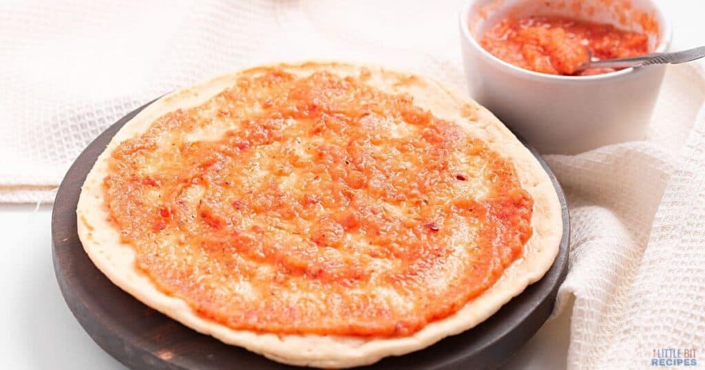 A large pizza crust topped with red sauce.