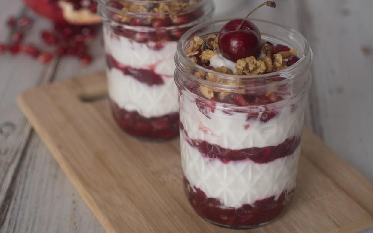 Mason jar full of cherry, pomegranate and yogurt.