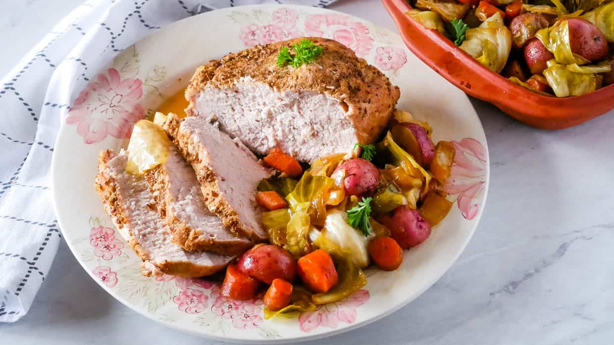 Oven roasted pork loin with potatoes, carrots and cabbage on a plate.