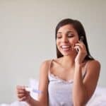 Pregnant woman holding a pregnancy test and revealing pregnancy on the phone.