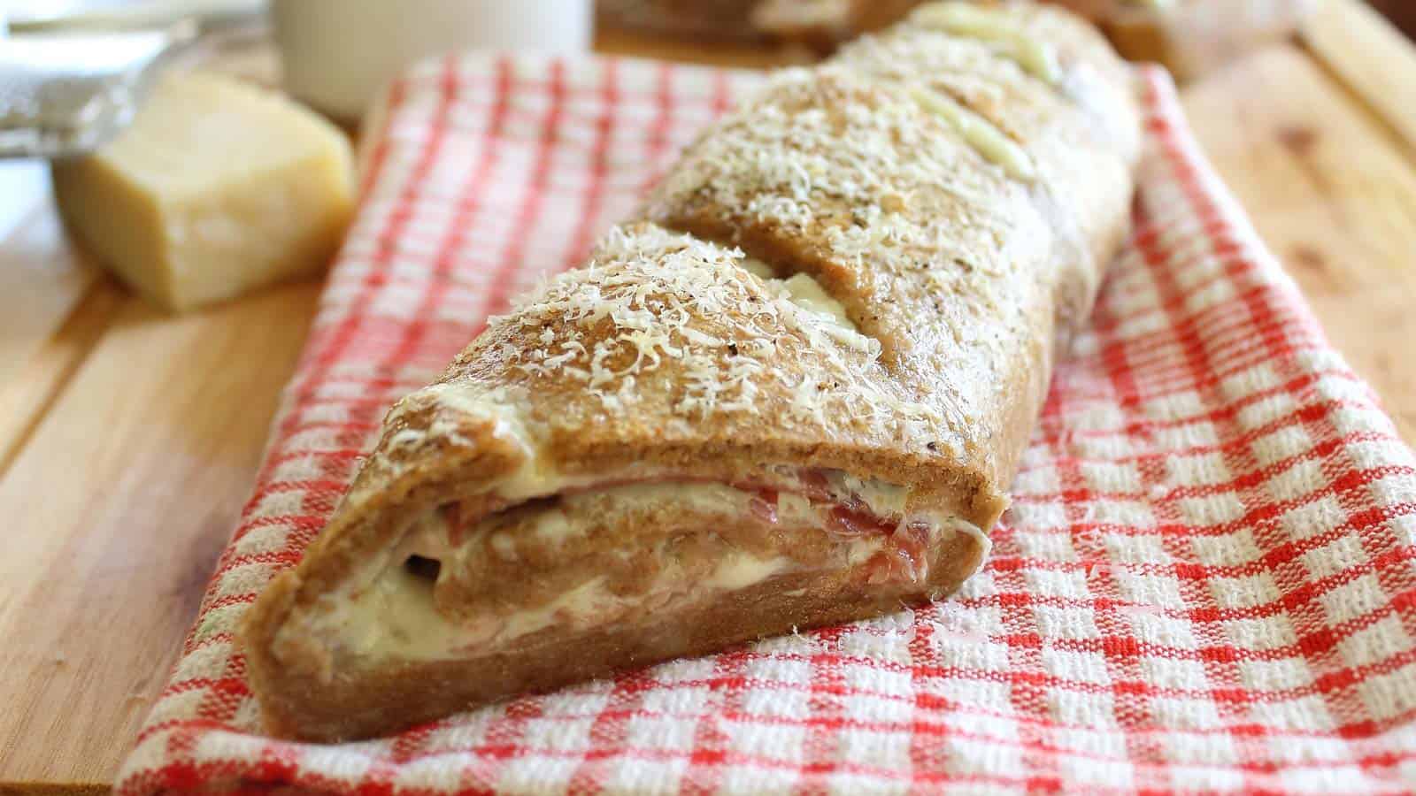 Prosciutto stromboli on a red and white kitchen towel.