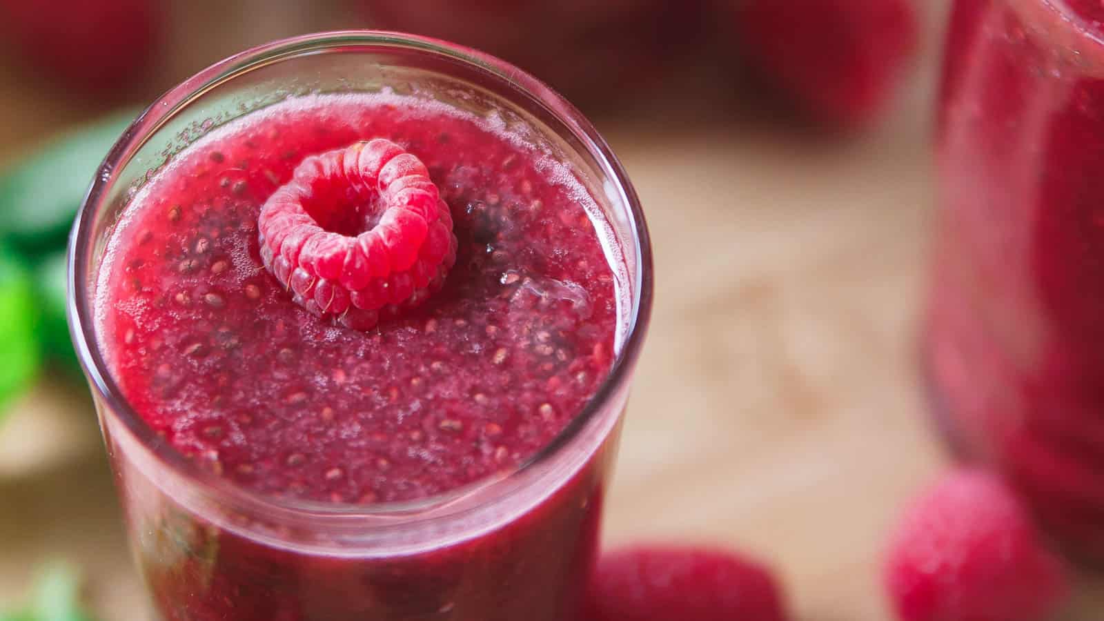 Raspberry chia lemonade in a glass garnished with a raspberry.