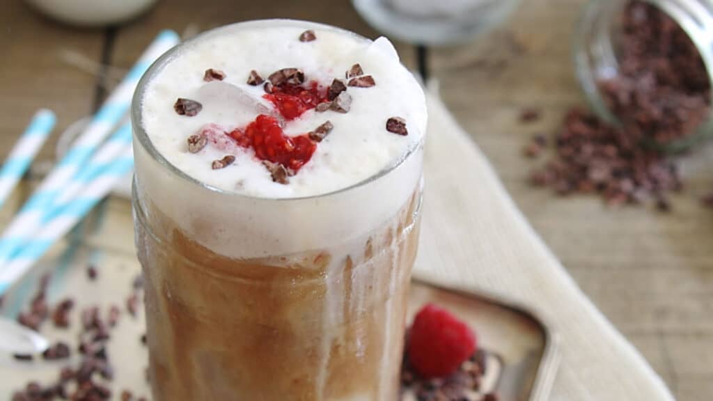 Raspberry iced coffee in a glass with foam.