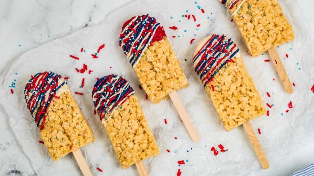 Rice krispie treats cut into popsicle shapes and drizzled with red, white and blue chocolate.
