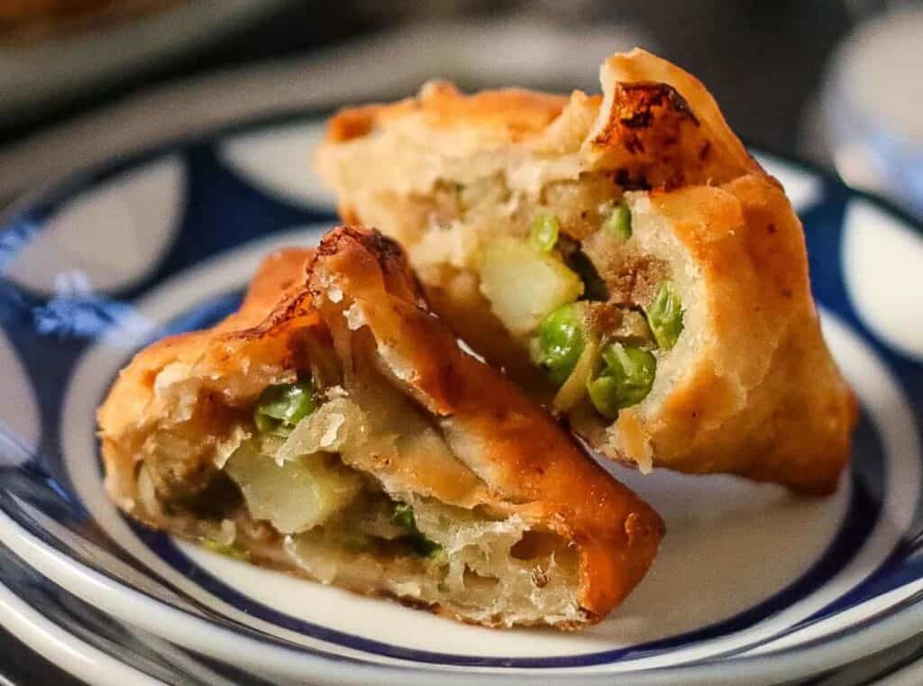 samosas with potato filling cut in half on a plate.