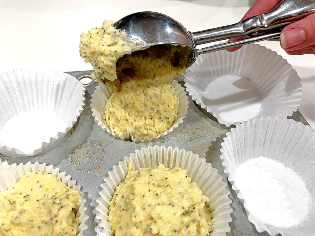 Scooping muffin batter into paper liners.