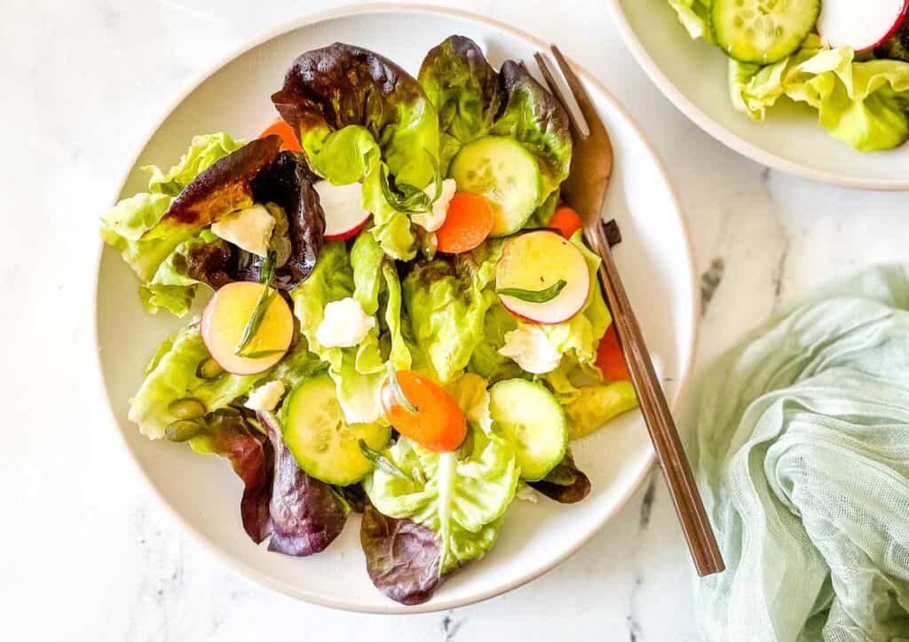 Side salad on a white plate with a copper fork.