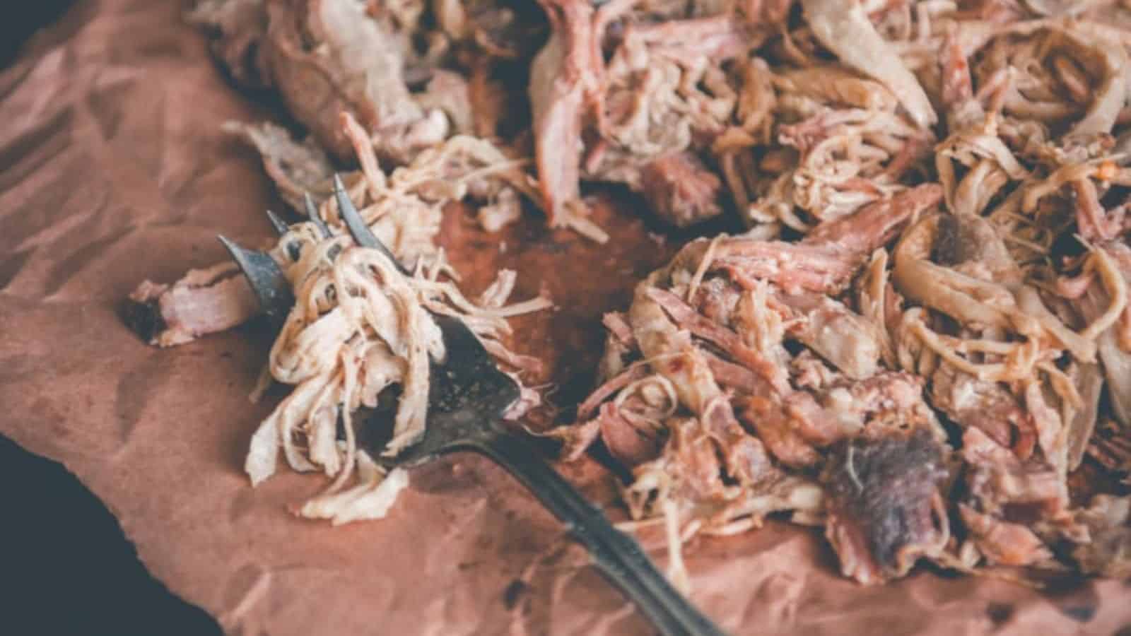 Shredded pulled pork butt with a fork.