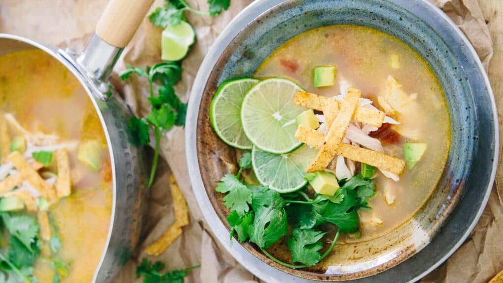 Sopa de lima in a bowl with lime slice garnish and cilantro.