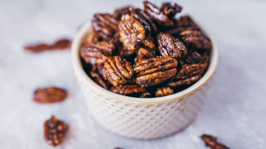 A small ceramic bowl filled with candied pecans.