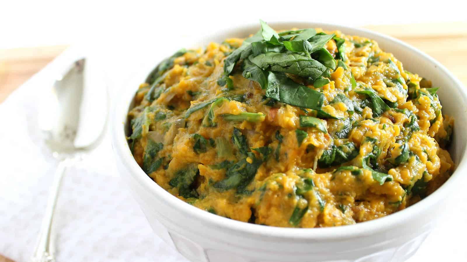 Mashed sweet potatoes with spinach and goat cheese in a white bowl.