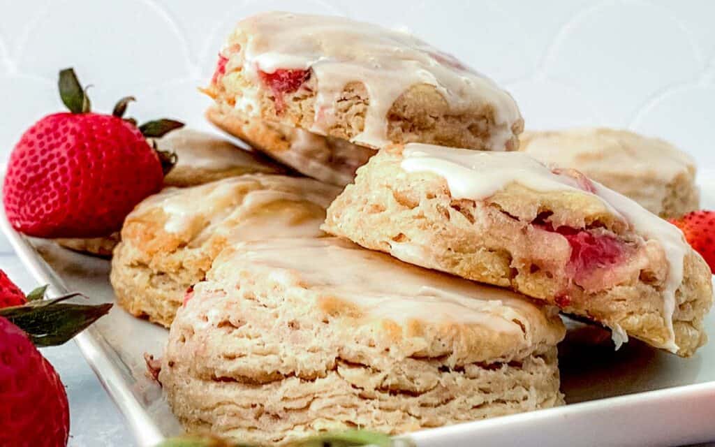 Stack of strawberry biscuits on a plate with berries in the background.