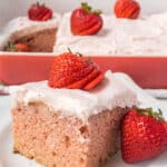 A slice of homemade strawberry cake with icing and strawberry on top.